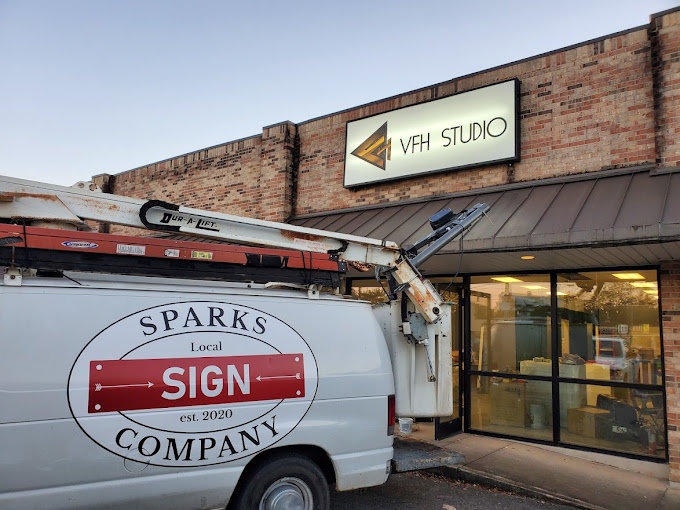 A sign van with its ladder boom raised beside a newly installed storefront sign