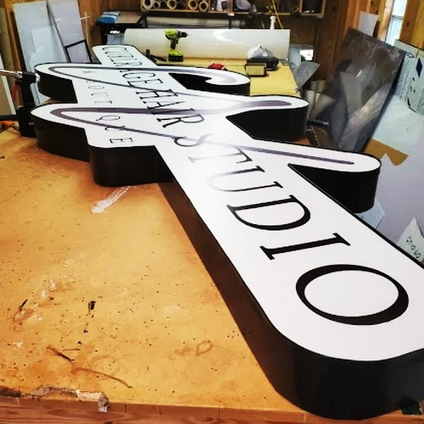 A shaped, lettered business sign being fabricated on a workbench in our Mobile sign shop