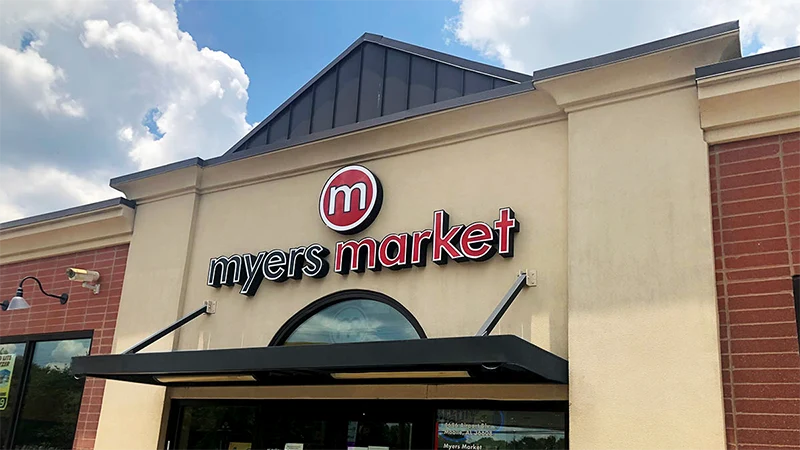 Red and black channel letters with a round logo over a grocery storefront