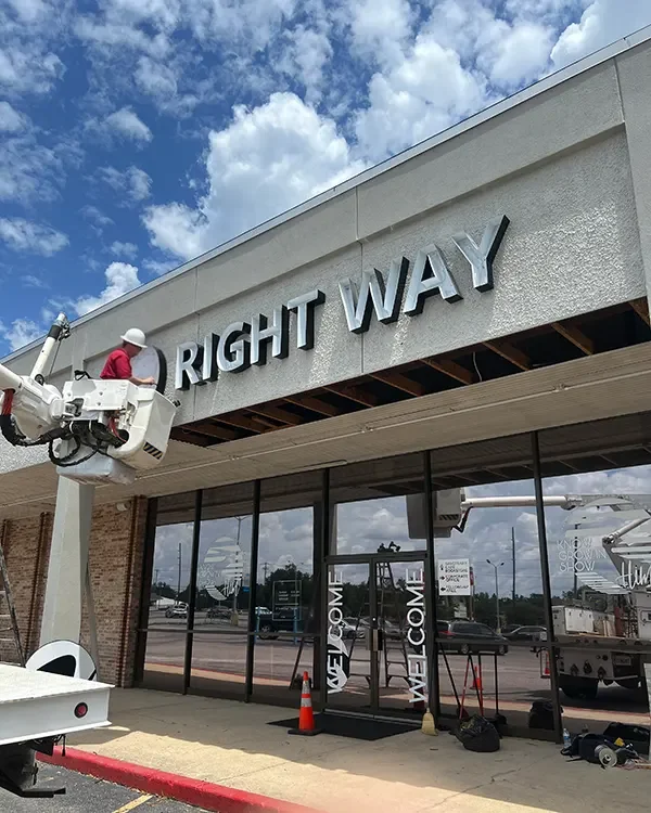 Channel letters being mounted on a storefront from a bucket truck lift