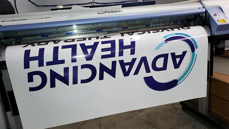 A physical therapy clinic's logo decal coming off the large-format printer in our shop