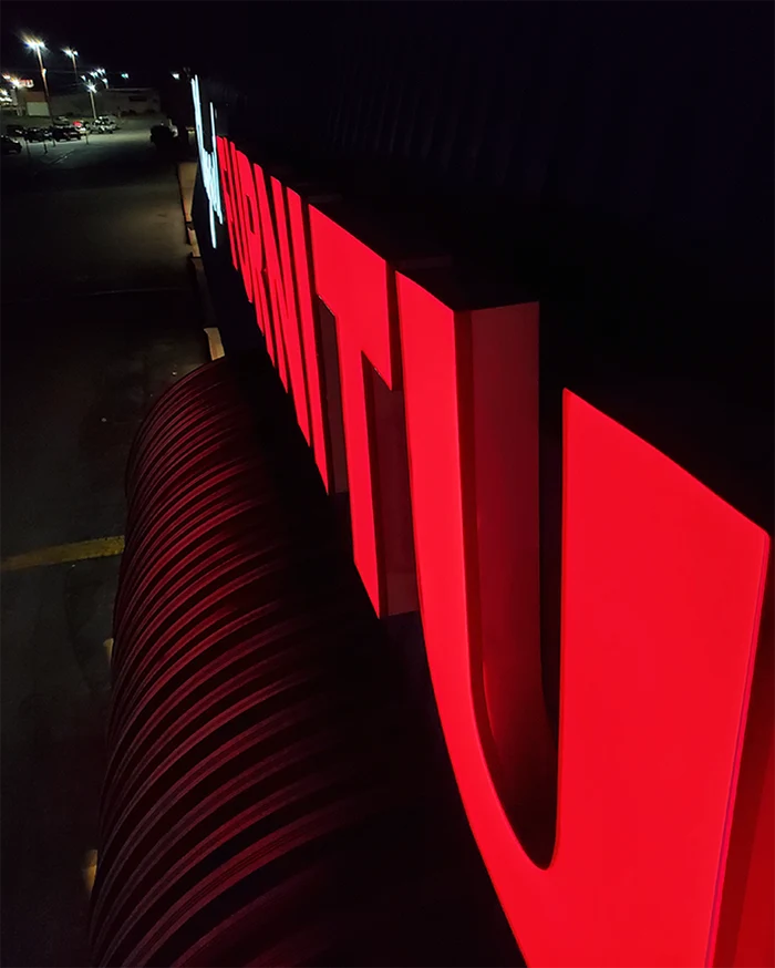 Red channel letters lit at night, seen along the front of the building