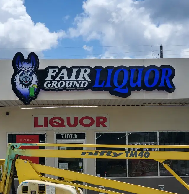 Fairground Liquor sign installed, daytime, with lift in foreground | Graphic Design | Sparks Sign Company