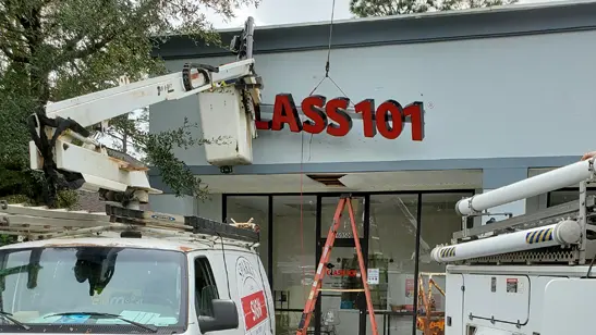 Installing Class 101 sign on raceway with work van boom | Sparks Sign Company