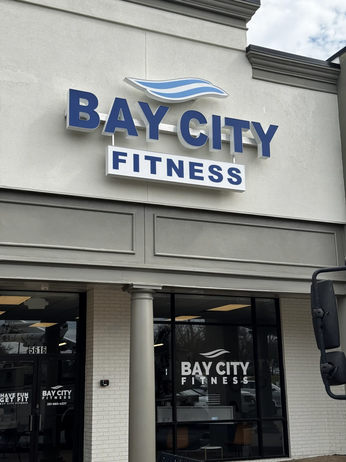 The Bay City Fitness sign in blue and white letters on a grey storefront
