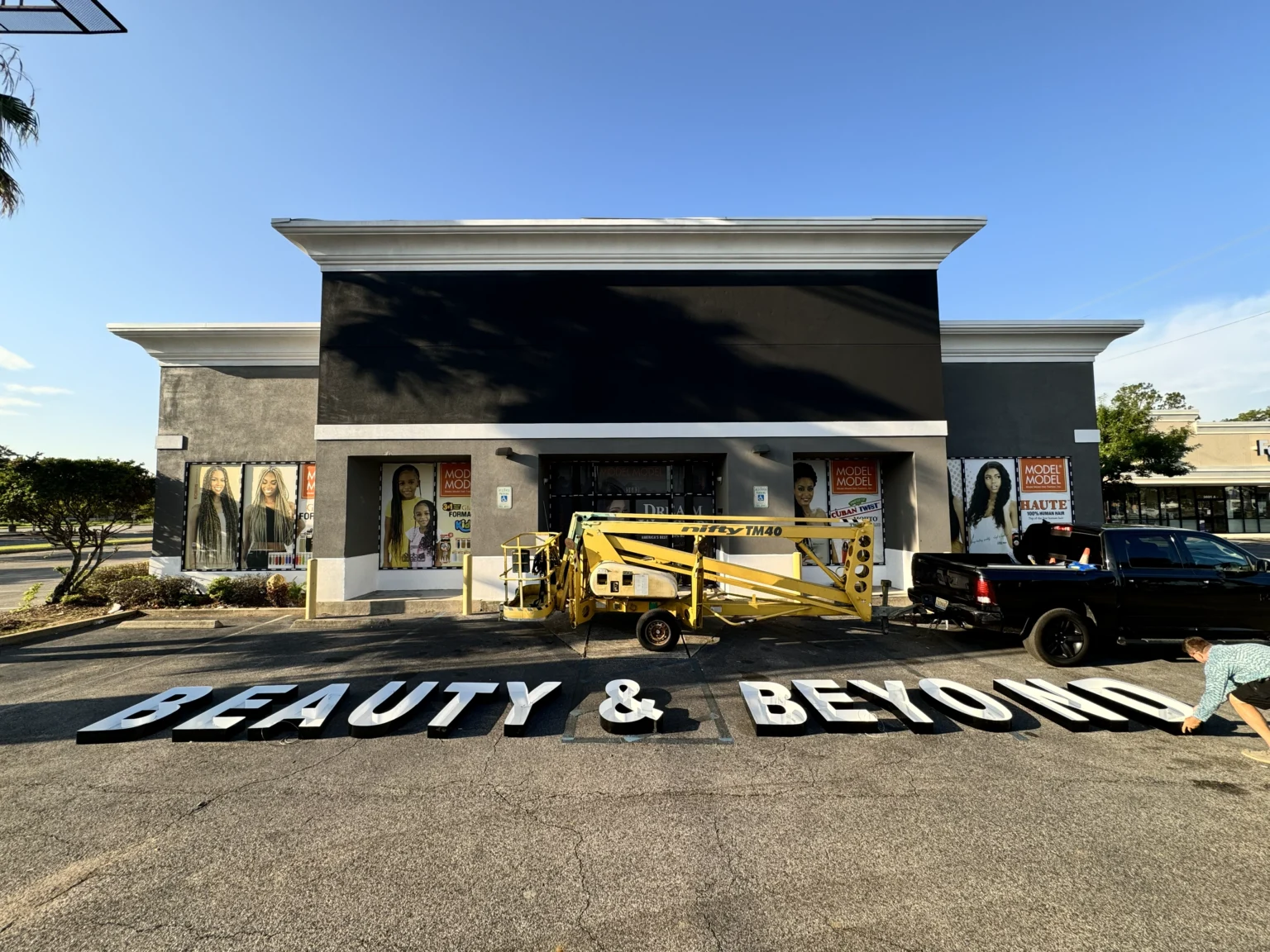 Beauty and Beyond channel letters laid out on the parking lot beside a lift, ready to be installed