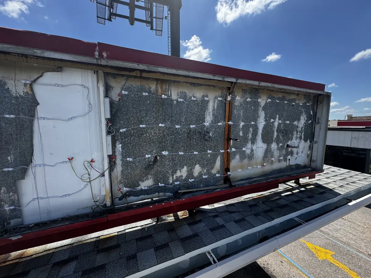A rooftop sign cabinet with its old faces off, the LED modules and worn backing exposed