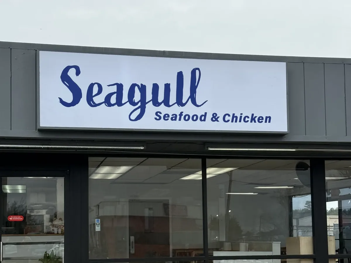 Seagull Seafood & Chicken's white cabinet sign with blue lettering above its storefront