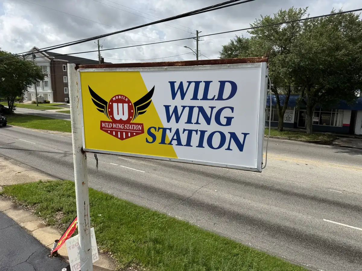 Wild Wing Station's yellow and white cabinet sign on a roadside pole