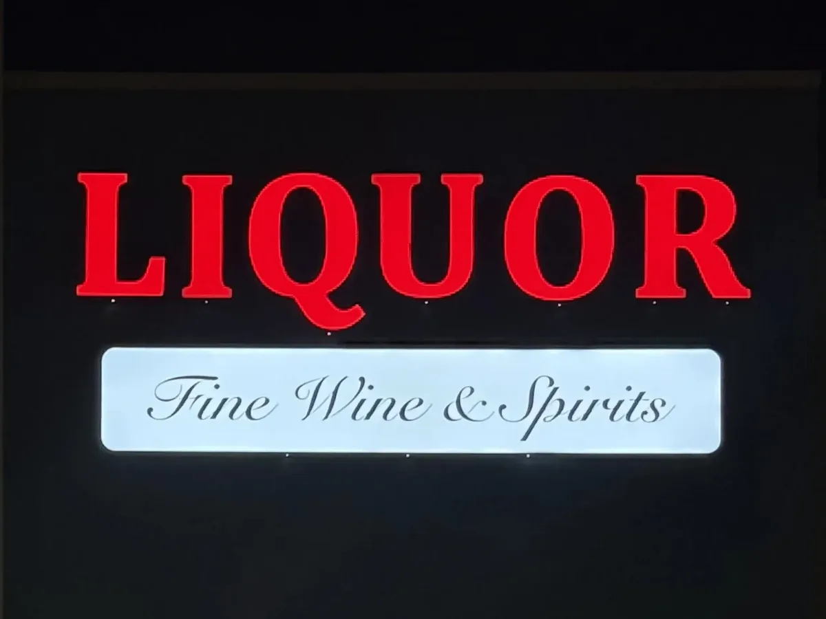 Front-lit red channel letters on a storefront at night, every letter face lit, above a lit white panel