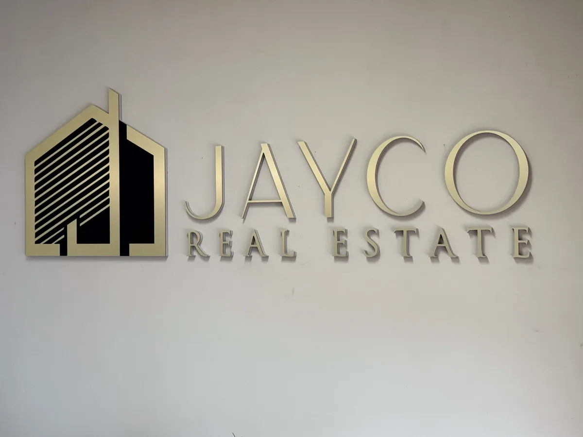 Jayco Real Estate gold and black dimensional logo and letters on an office wall