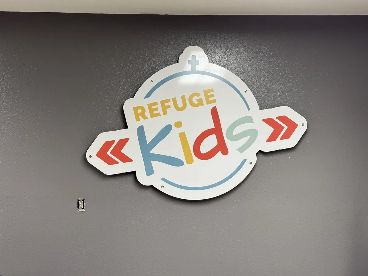 Refuge Kids logo panel on a dark grey interior wall