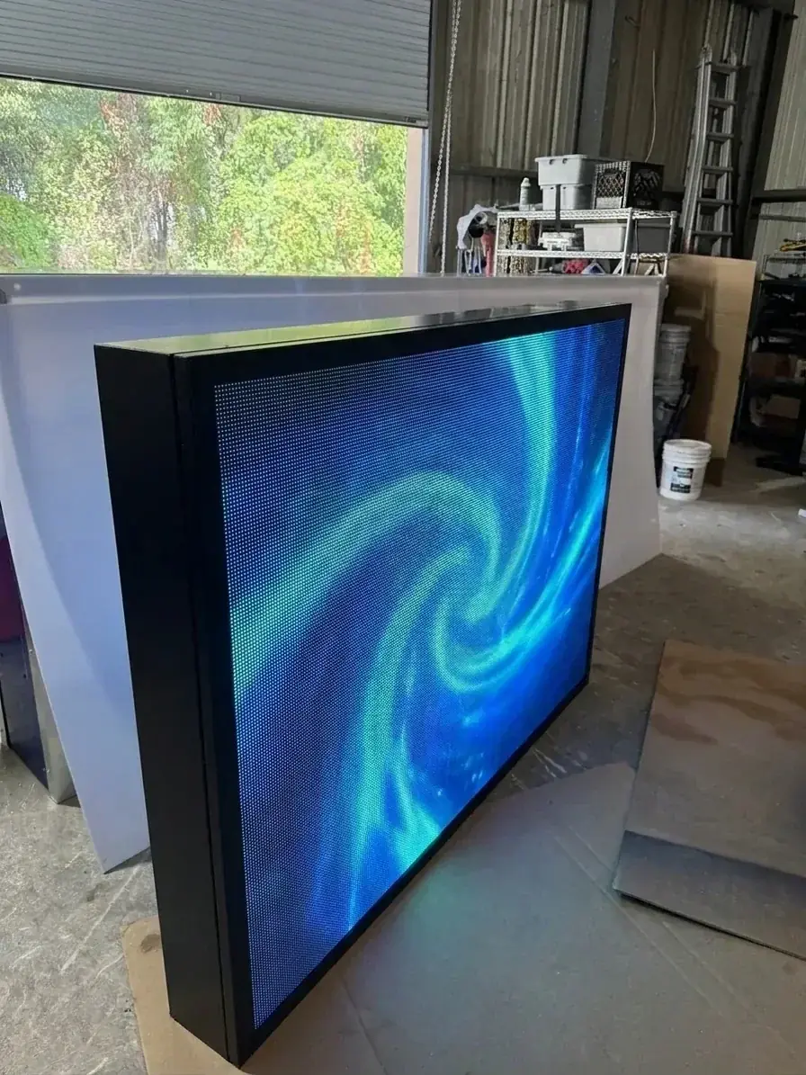 Generated placeholder illustration: a double-sided outdoor LED display cabinet lit in blue, its LED pixels visible up close, on a sign shop floor