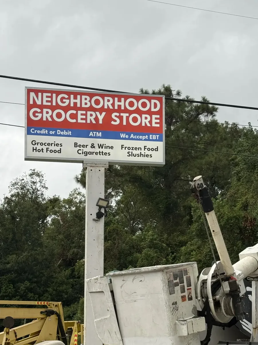 Bucket truck and a towable lift parked under a finished grocery store pylon sign cabinet