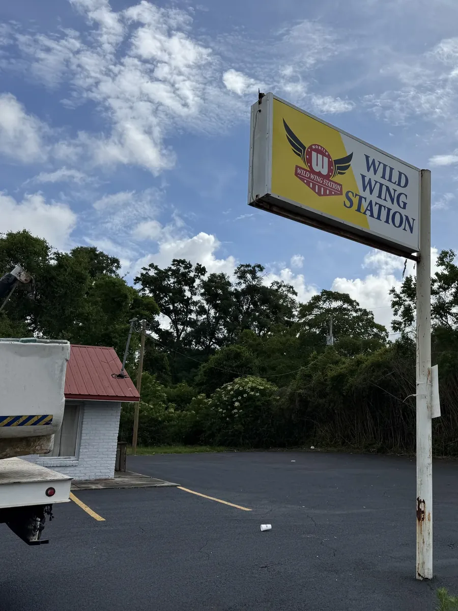 Wild Wing Station pole sign by the parking lot, with a bucket truck parked beside it