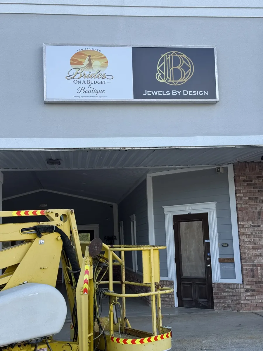 The Brides on a Budget & Boutique and Jewels By Design sign on a storefront wall, with a towable lift's basket below