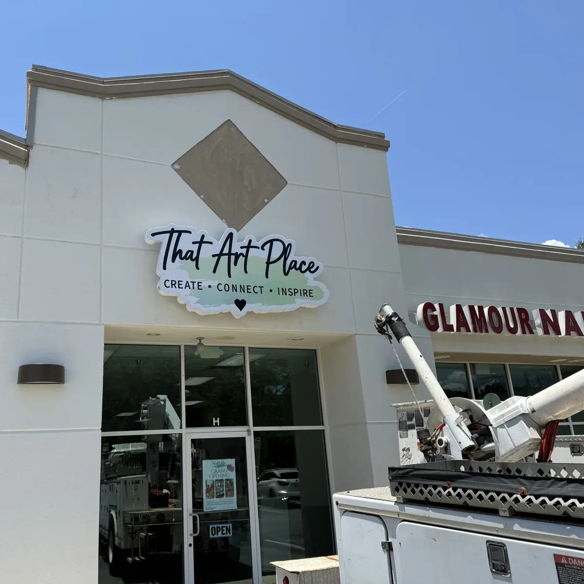 That Art Place's contour-cut sign on a strip-center front, with a bucket truck parked below it
