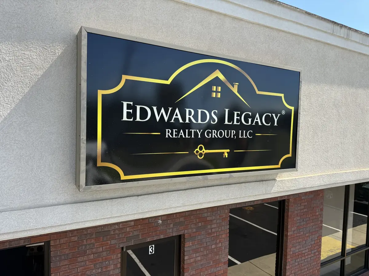 Edwards Legacy Realty Group wall cabinet sign, black and gold, on the storefront fascia