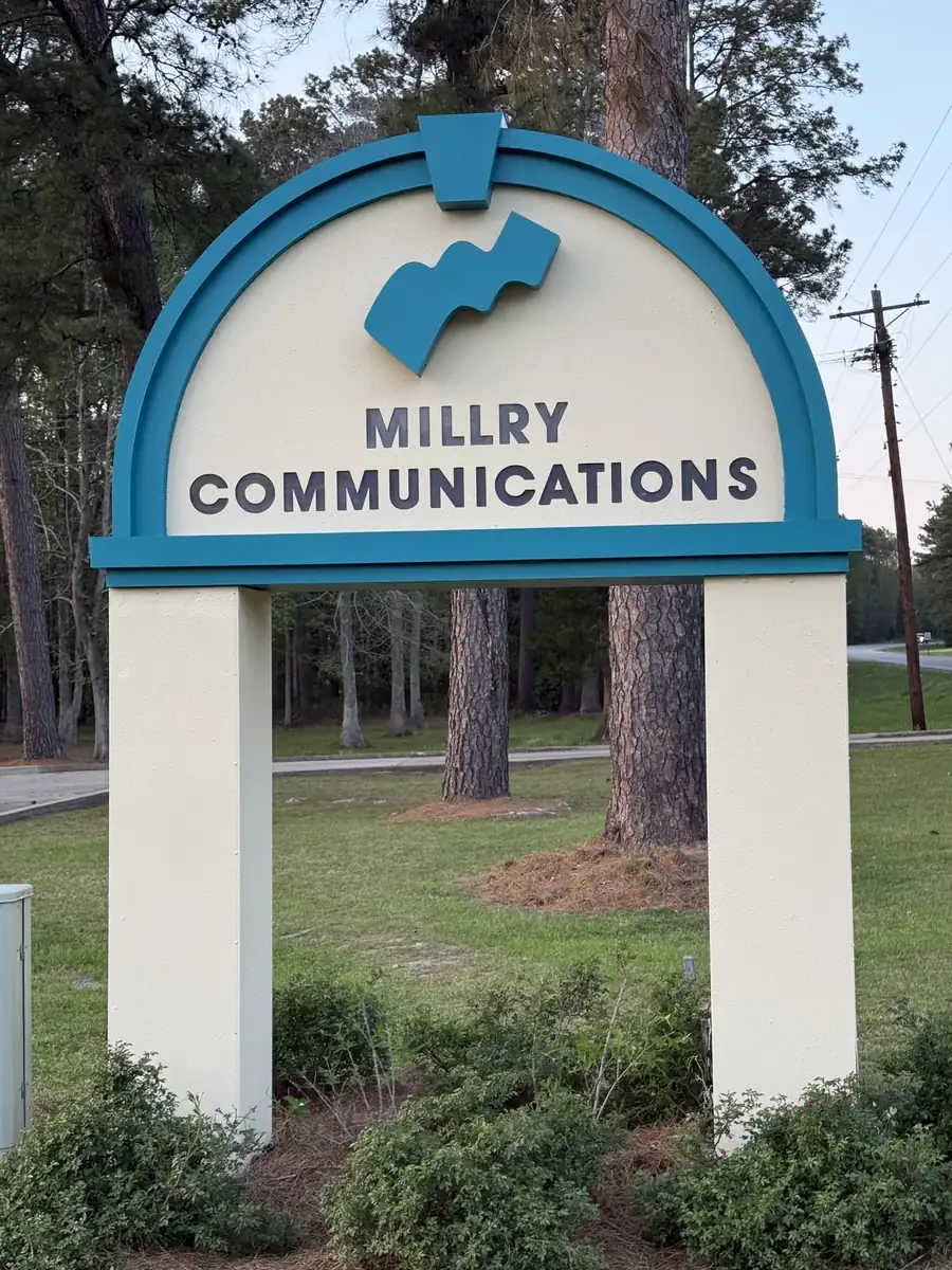 Millry Communications arched teal and cream monument sign with raised letters, front view