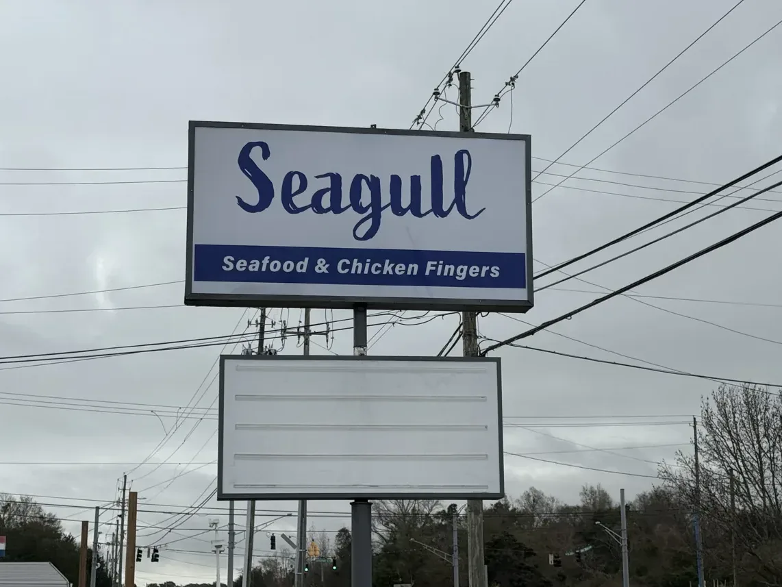 The Seagull Seafood & Chicken Fingers pylon sign on its steel pole by the road, with a blank panel below