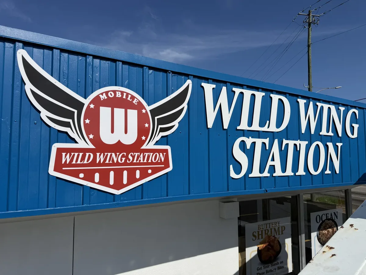 Wild Wing Station winged logo and letters on the blue metal fascia