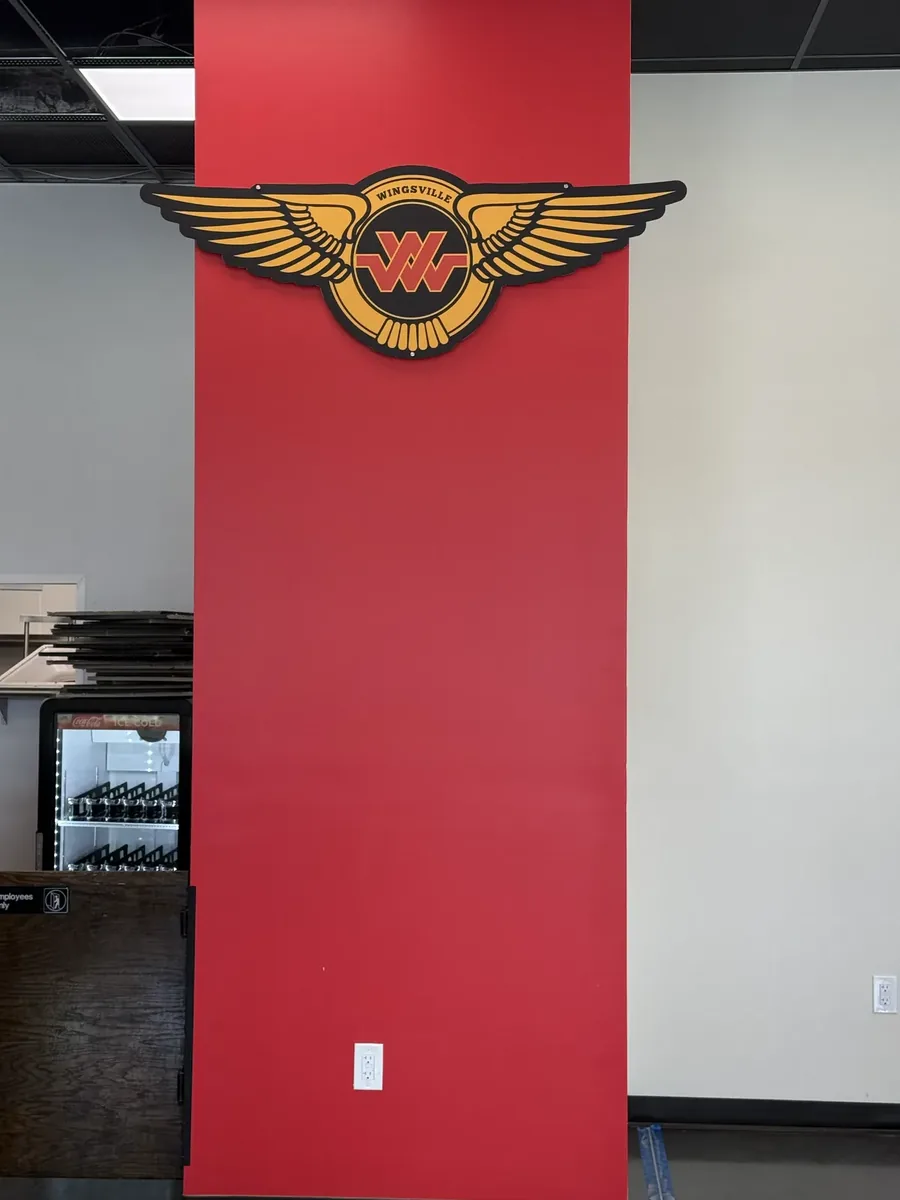 Wingsville winged logo sign on a red interior column