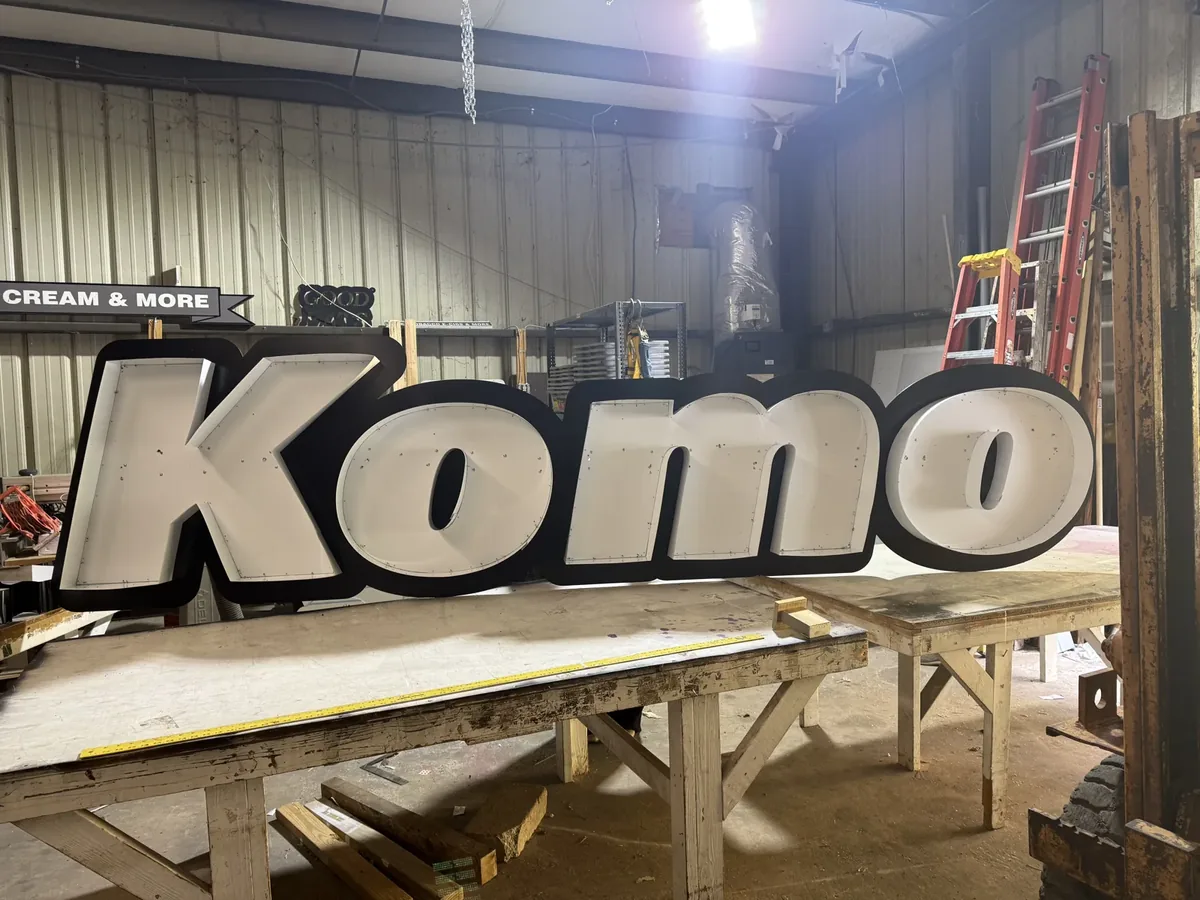Komo channel letters standing on a table in the sign shop