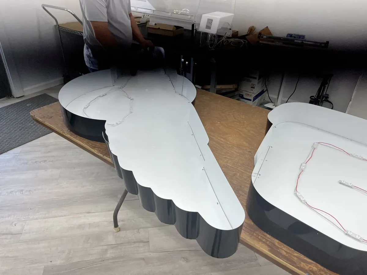 Open-back Wingsville channel letters with their LED modules wired inside, on a table in the sign shop