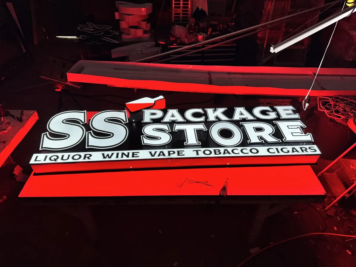 The SS Package Store sign test-lit red on a table in the sign shop