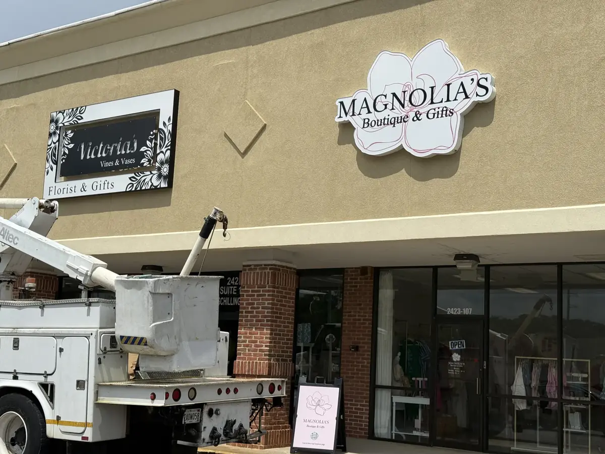 Bucket truck parked under the new Magnolia's Boutique & Gifts sign on a strip-center storefront