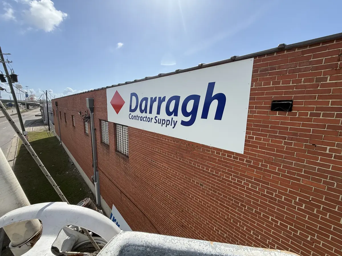 The Darragh Contractor Supply panel sign on a brick wall, seen from a bucket truck bucket
