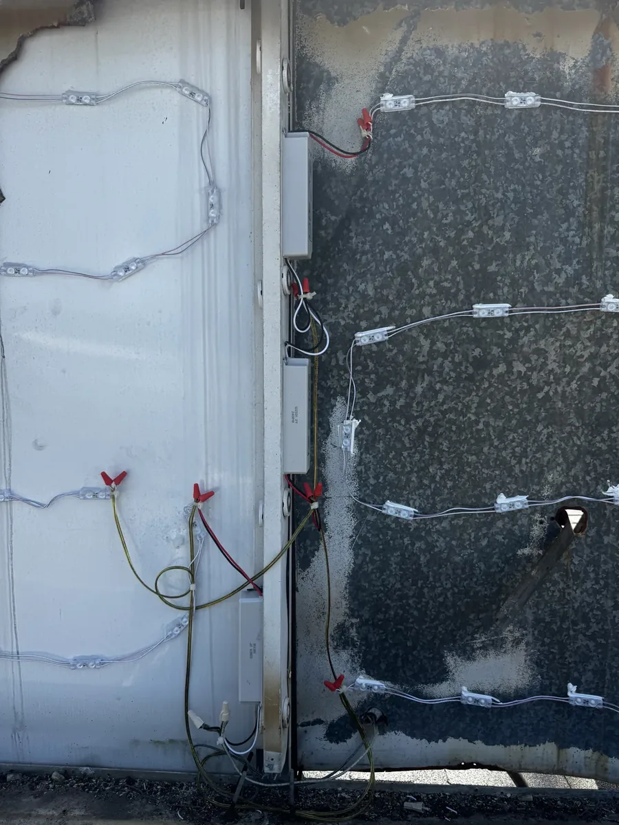 Inside an opened sign cabinet: chains of LED modules, power supplies and wiring along the cabinet walls