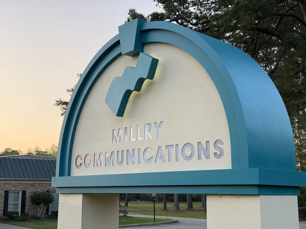The same monument sign finished at dusk, its cut-out lettering lit from inside and its raised logo glowing at the edges