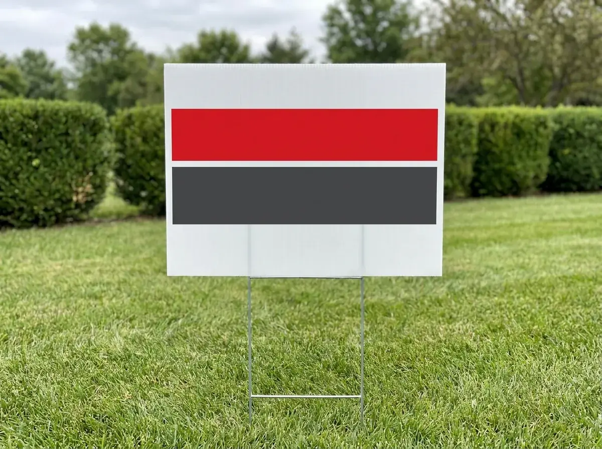 A white corrugated plastic yard sign with a red and a charcoal band, standing in a lawn on a wire H-stake