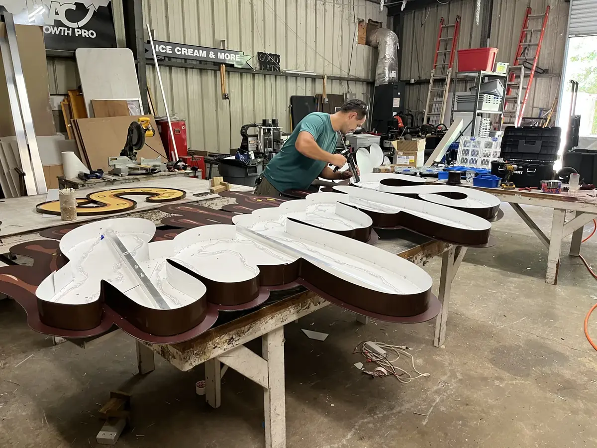 A Sparks crew member building channel letters on a shaped backer at a shop bench