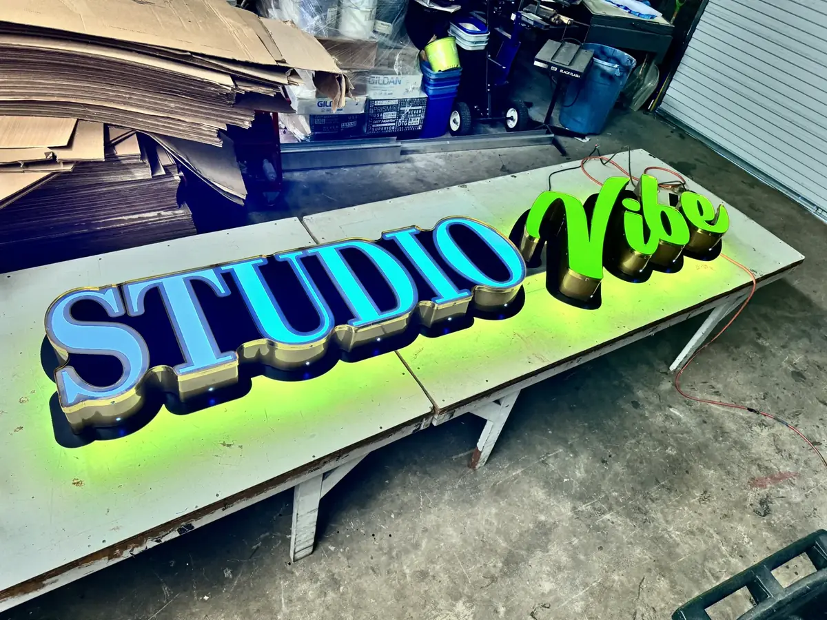 Studio Vibe channel letters lit on the shop tables during a light test