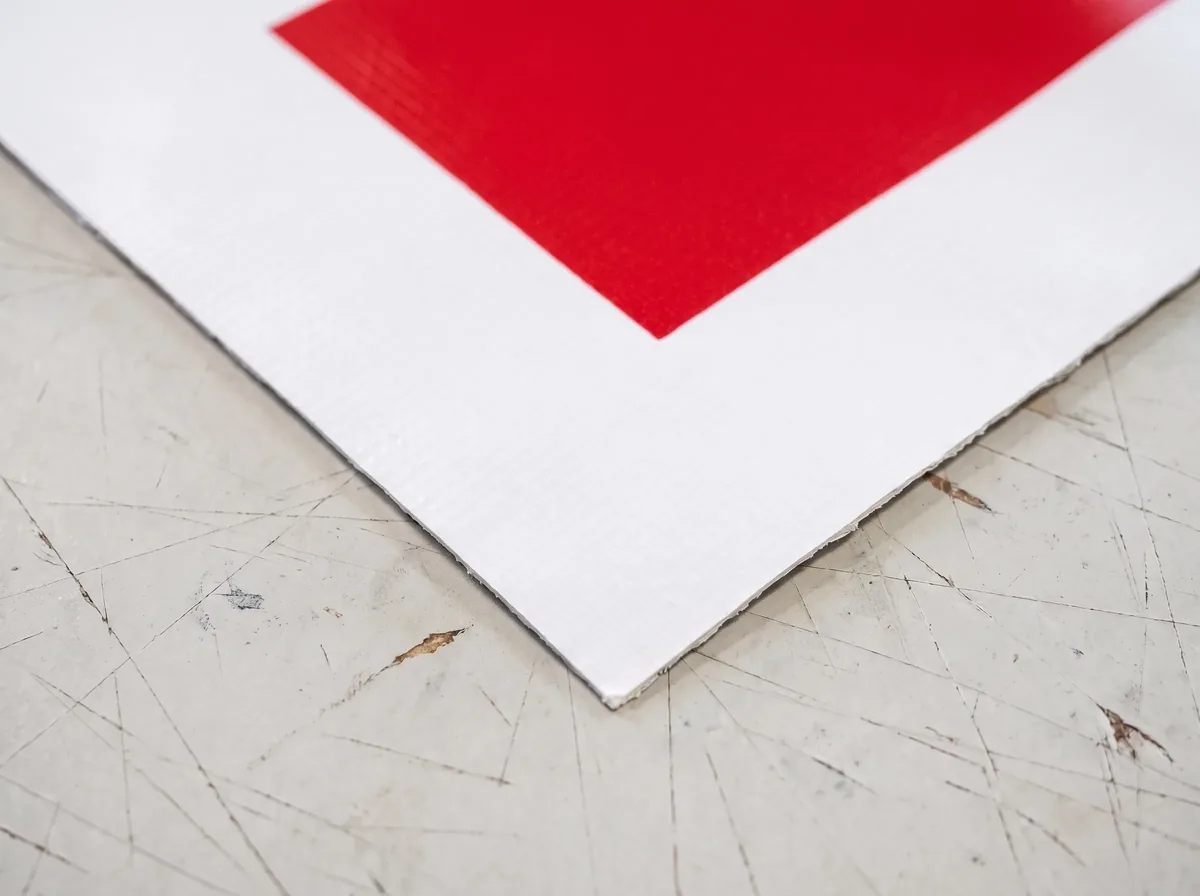 Close-up of a vinyl banner corner with a raw cut edge and no hem or grommet