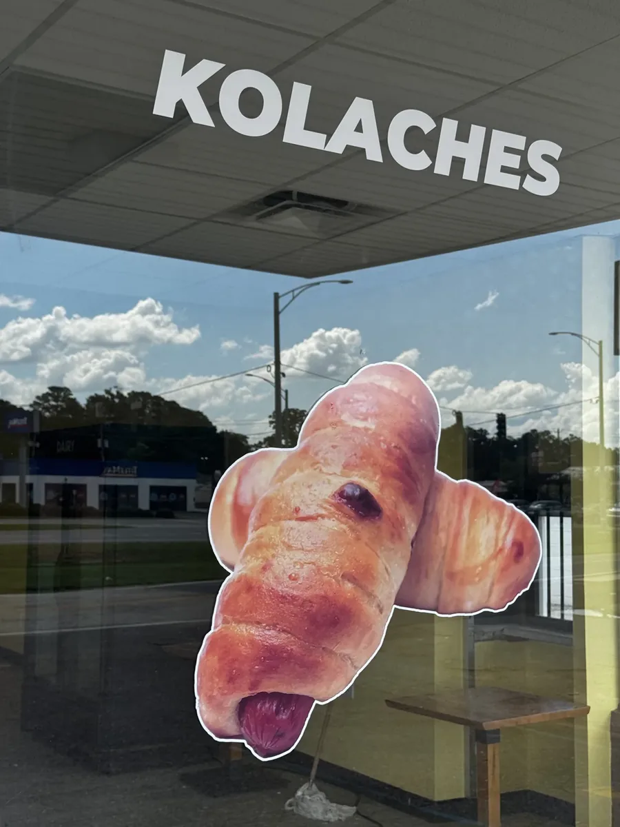 Lickin Good Donuts window with kolaches lettering above a cut-out kolache graphic